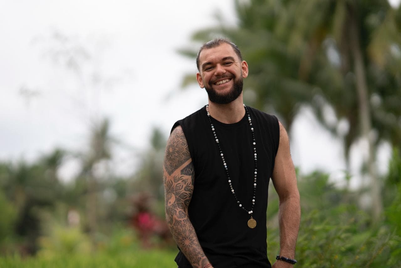 Joshua Sting sitting beside a rice field, looking toward the camera
