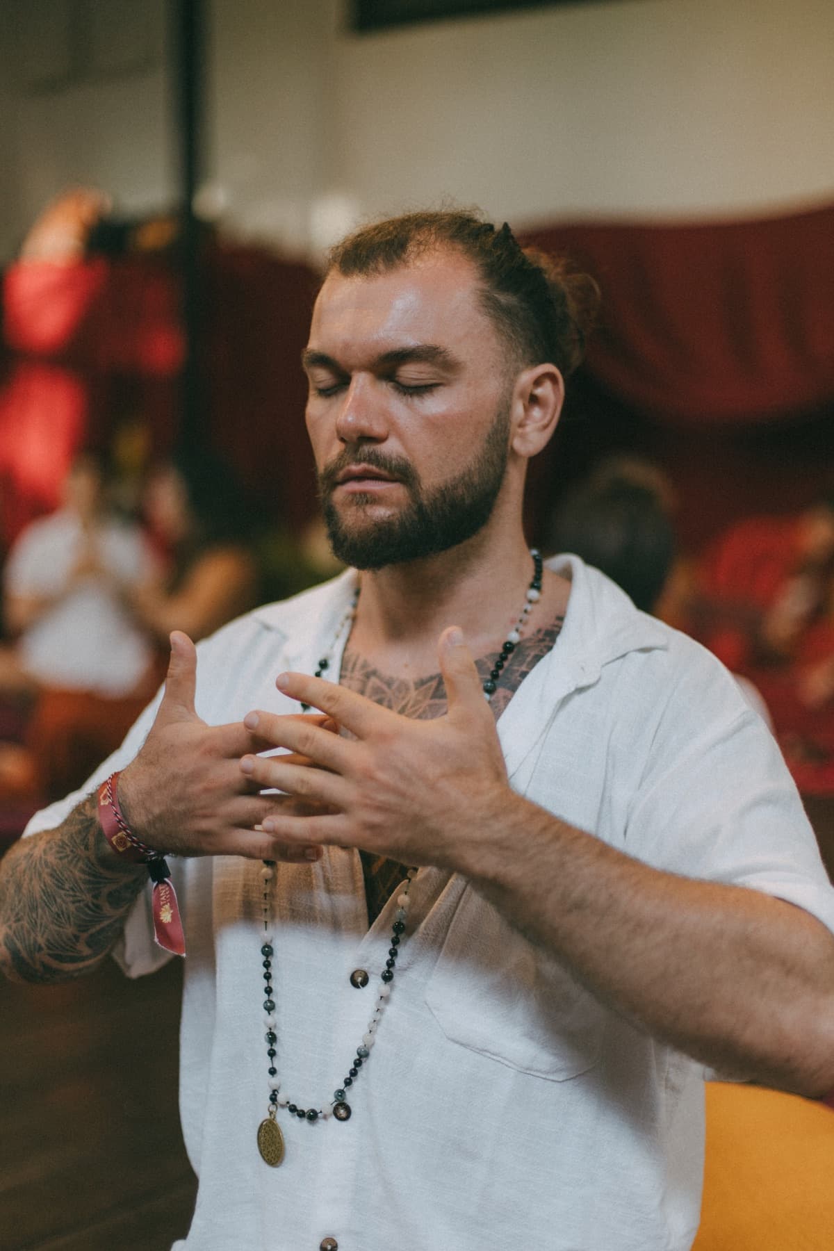 Joshua Sting with his eyes closed and a hand on his heart, wearing mala beads
