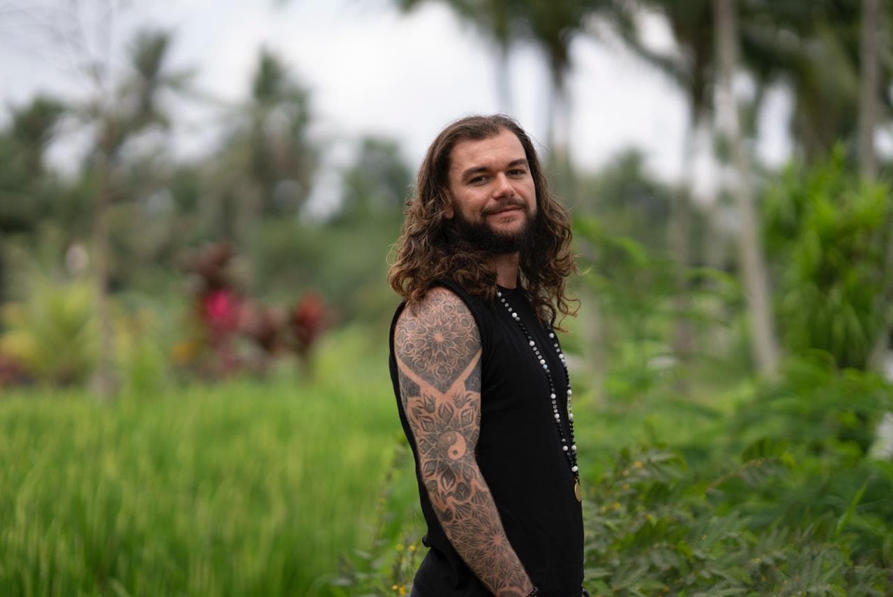 Joshua Sting standing beside a rice field, glancing toward the camera